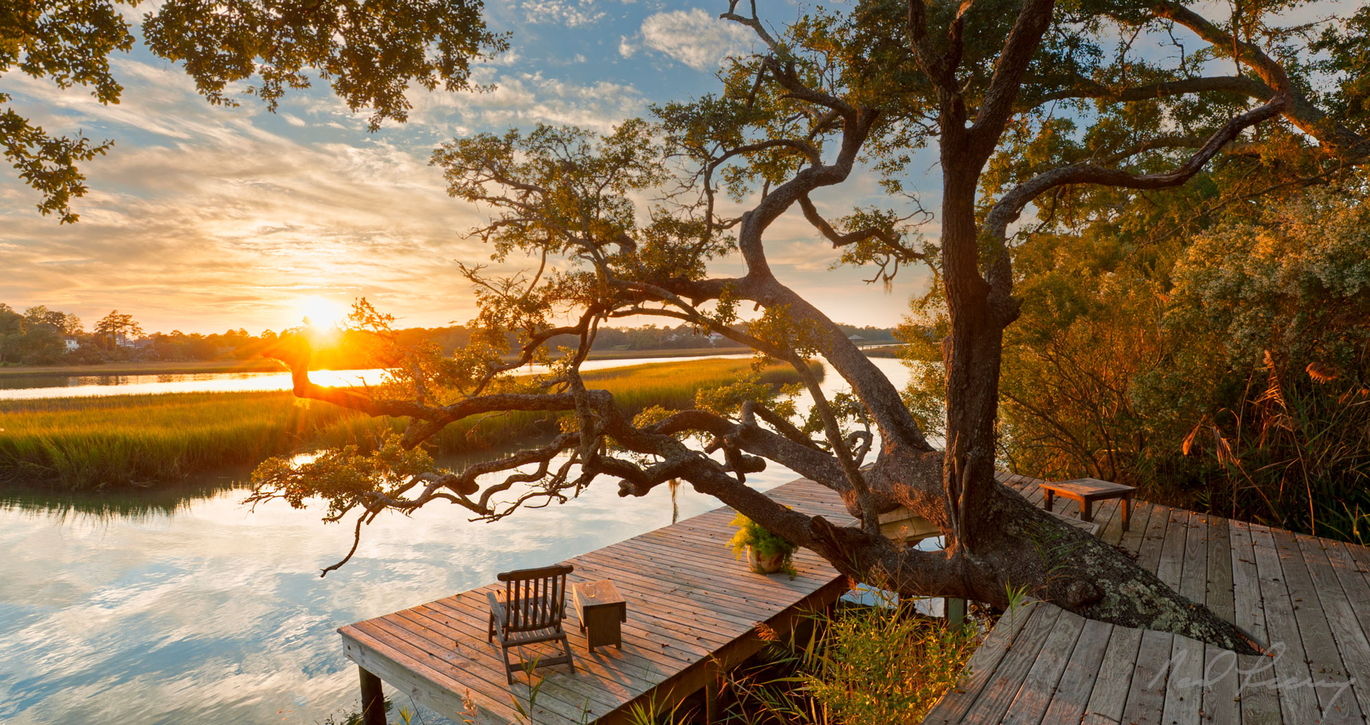 Wooden dock on waterway at sunset